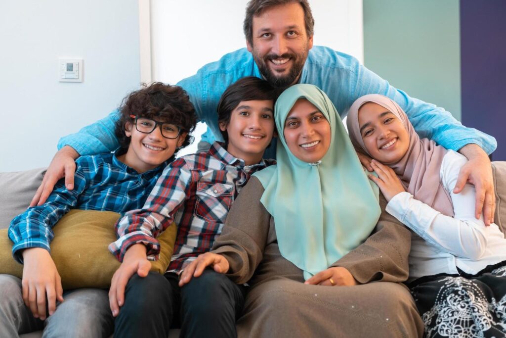 Portrait photo of an arab muslim family sitting on a couch in the living room of a large modern house. Selective focus Stock Free