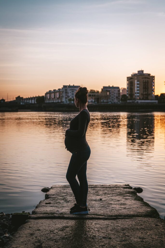 Pregnant Woman Enjoying Sunset by the River Free Photo