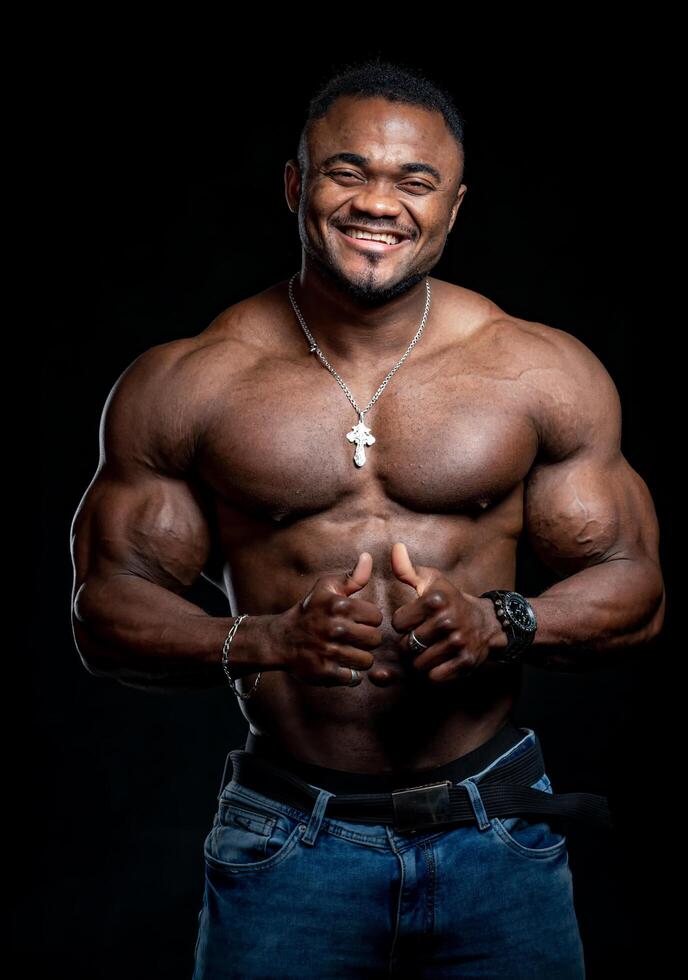 Professional african american sportsman posing on camera with no shirt. Black studio background. Smiling athlete. Closeup. Stock Free