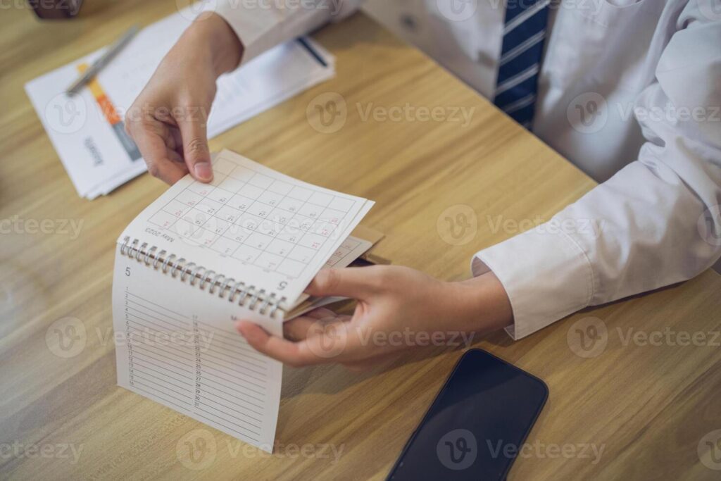 Professional setting a schedule in a planner with a pen, amidst a business-focused workspace Pro Photo