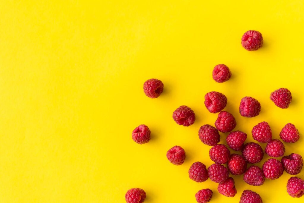 Raspberries on Flat Yellow Background Free Photo