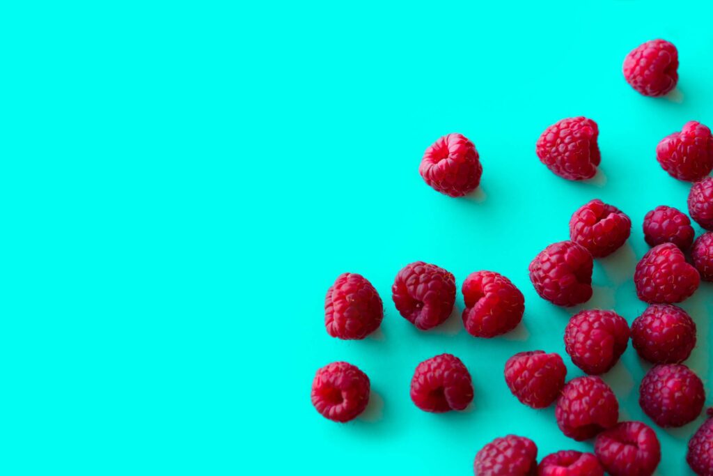 Raspberries with Blue Background Space for Text Free Photo