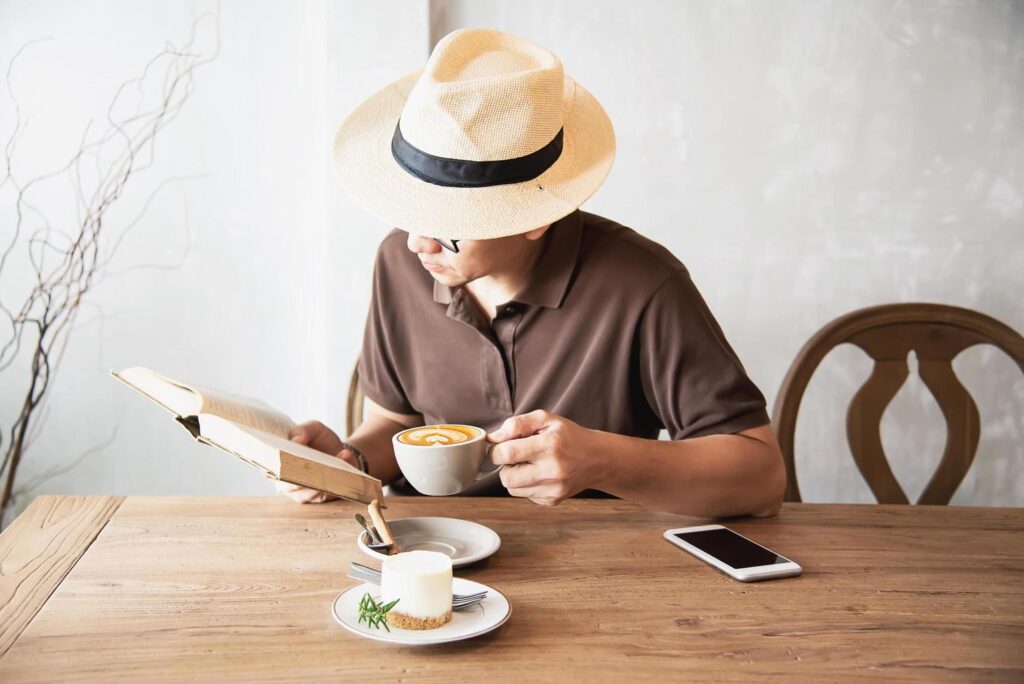 Relax Asian man drink coffee and read book in a modern style coffee shop – people with coffee cup easy lifestyle concept Stock Free