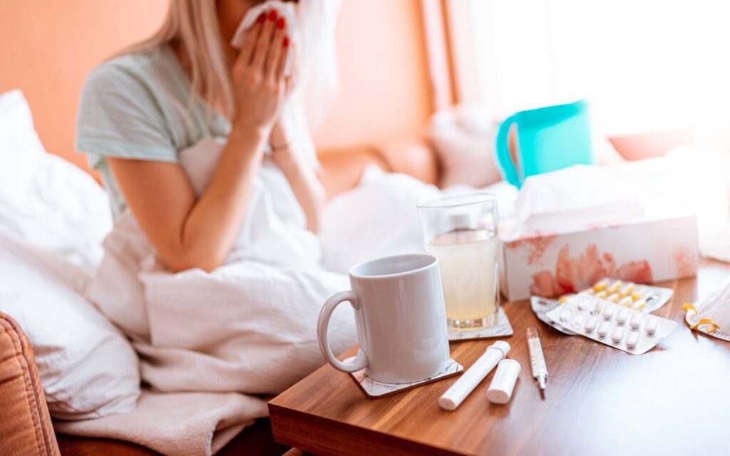 Sick Woman Blowing a Nose While Sitting on a Bed Free Photo