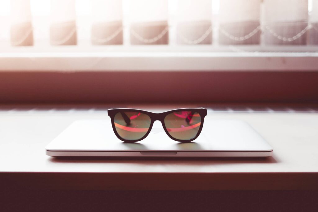 Sleek Sunglasses on Closed MacBook Laptop Free Photo