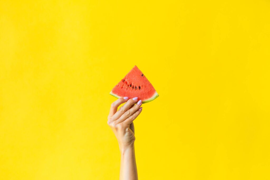 Slice of Watermelon in Woman Hand on Bright Yellow Background Free Photo