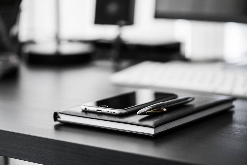 Smartphone, Diary and Silver Pen on Black Workspace Desk Free Photo