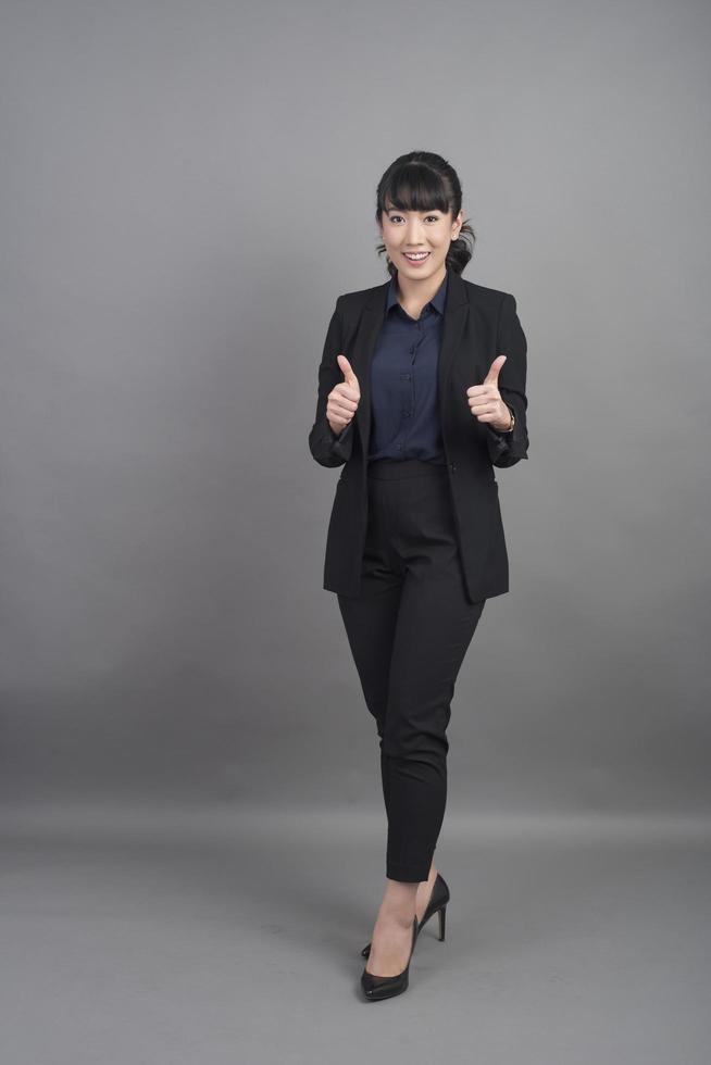 Smiling business woman in blazer on grey background Stock Free