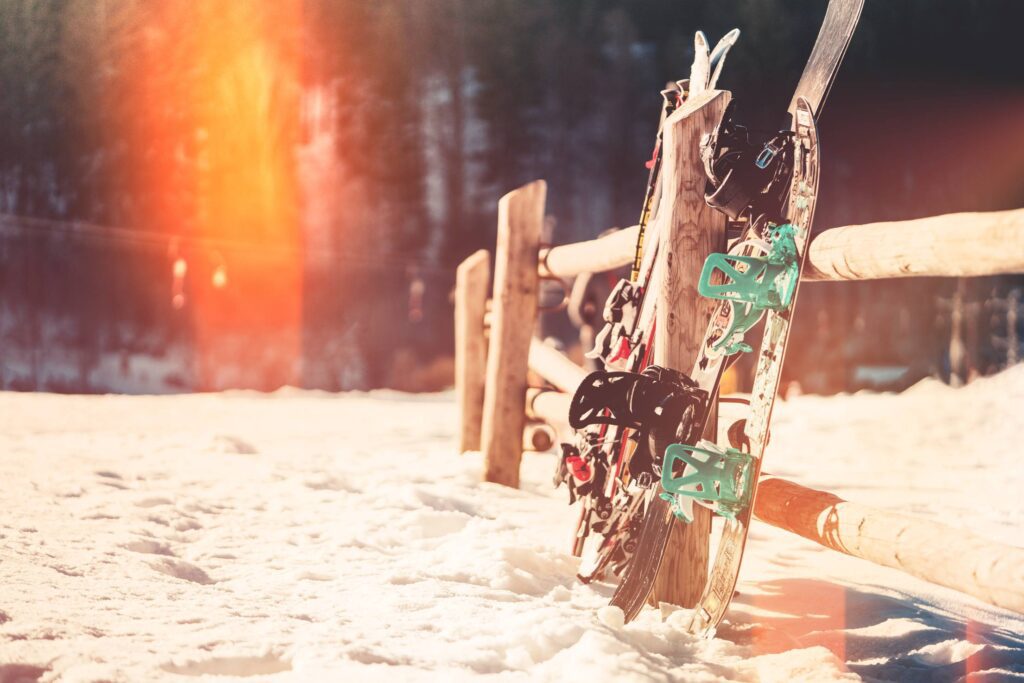 Snowboards and Skis Leaning Against Wooden Fence Free Photo