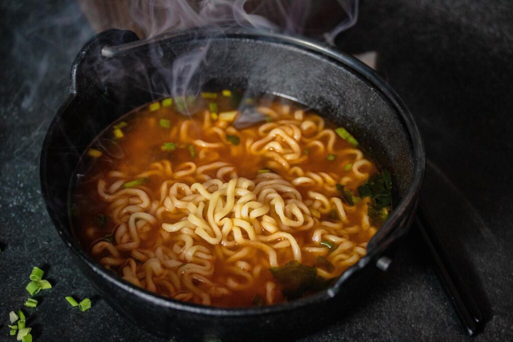 Spicy Korean Instant Noodles with Wakame Seaweed in a Black Iron Pot, Korean Food Traditional Style Stock Free