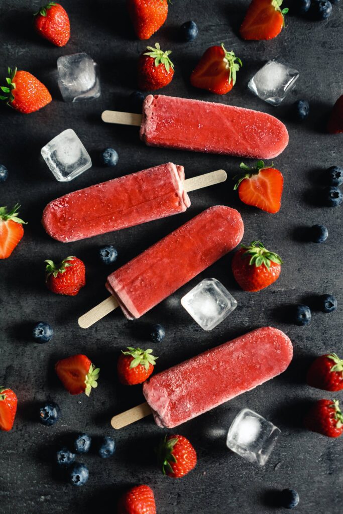 Strawberry Ice Lollies with Fresh Blueberries on Black Background Free Photo