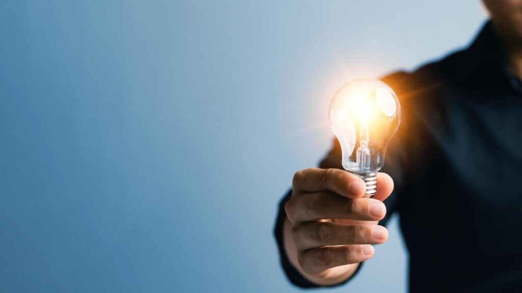 Successful Innovation through ideas and inspiration ideas. Human hand holding light bulb to illuminate, idea of creativity and inspiration concept of sustainable business development. Stock Free