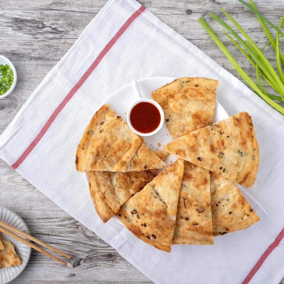 Taiwanese food – delicious flaky scallion pie pancakes on bright wooden table background, traditional snack in Taiwan, top view. Stock Free