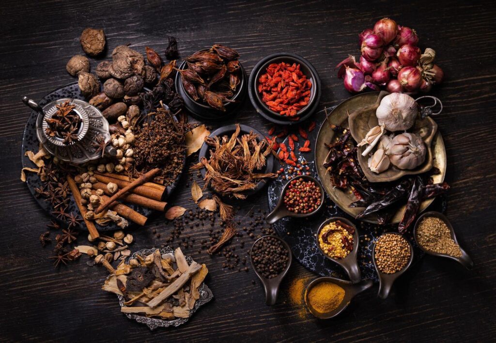 Thai native food, spices herbs, and various ingredients taken from top view angle. Group of hot and spicy dry vegetables, nuts, and grains for making Asian food on wooden background. Dark tone photo Stock Free