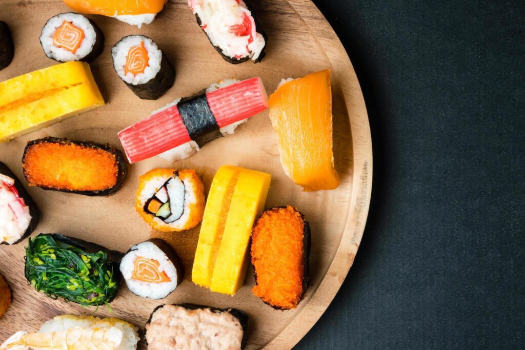 Top view of Sushi set on wooden plate on black background, Japanese food. Free space for text Stock Free