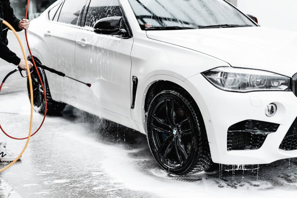 Washing White SUV in Self Service Car Wash with a Wap Hose Free Photo