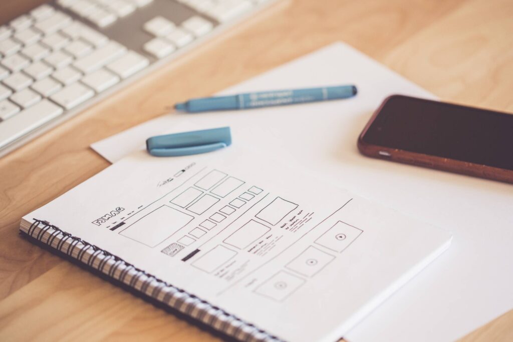 Web Designer Sketching a Wireframe Layout Ideas in a Notebook Free Photo