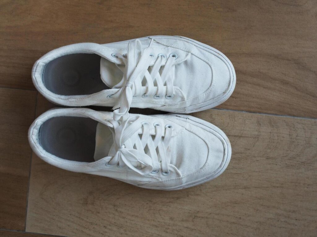 white canvas shoes on green and wooden backgrjound classic style easy and smooth life style Stock Free