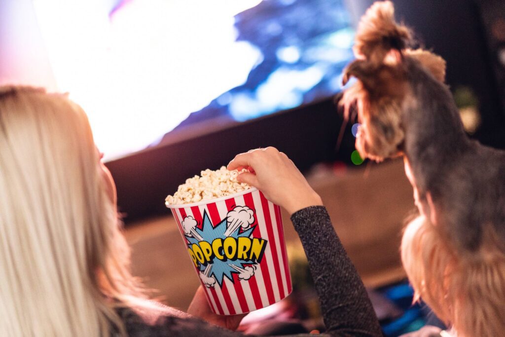 Woman and Her Dog are Watching a Movie and Eating Popcorn Free Photo