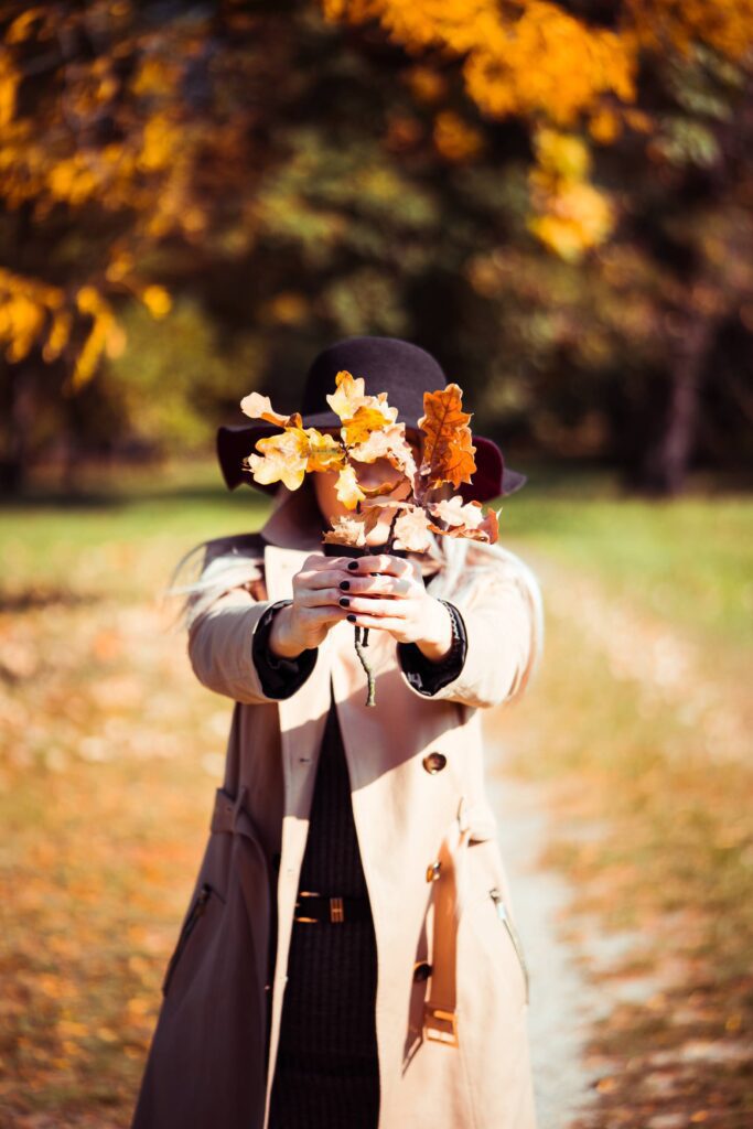 Woman Covering Her Face with Autumn Leaves Free Photo