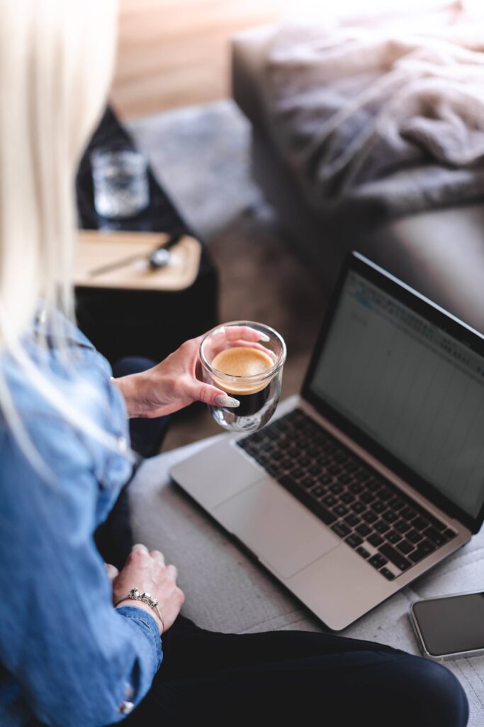 Woman Drinking Coffee and Working Remotely on Laptop at Home Free Photo