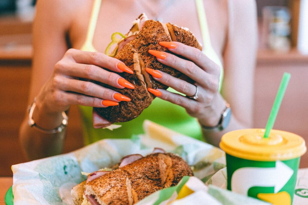 Woman Eating Sandwich in the Subway Restaurant Free Photo