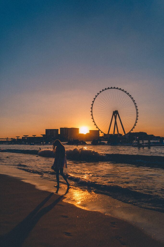 Woman Enjoying a Walk on a Public Beach in Dubai Under the Ain Dubai Wheel Free Photo