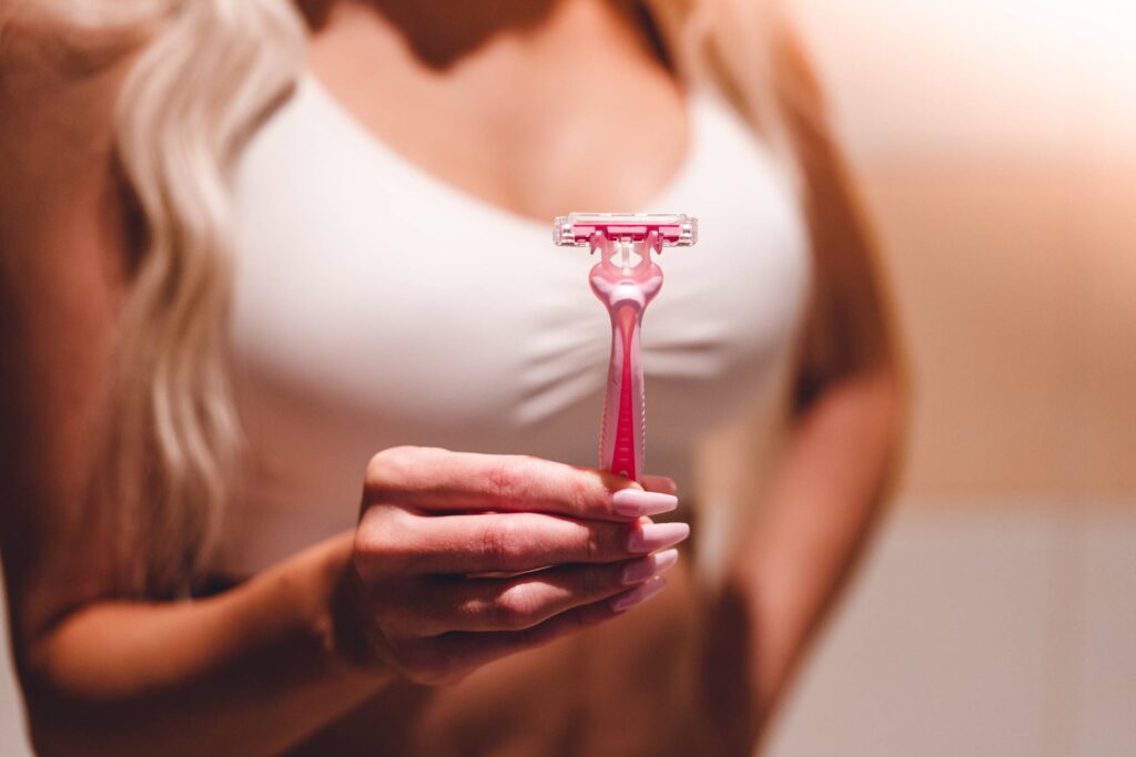 Woman Holding a Pink Shaving Razor in Her Hand Free Photo