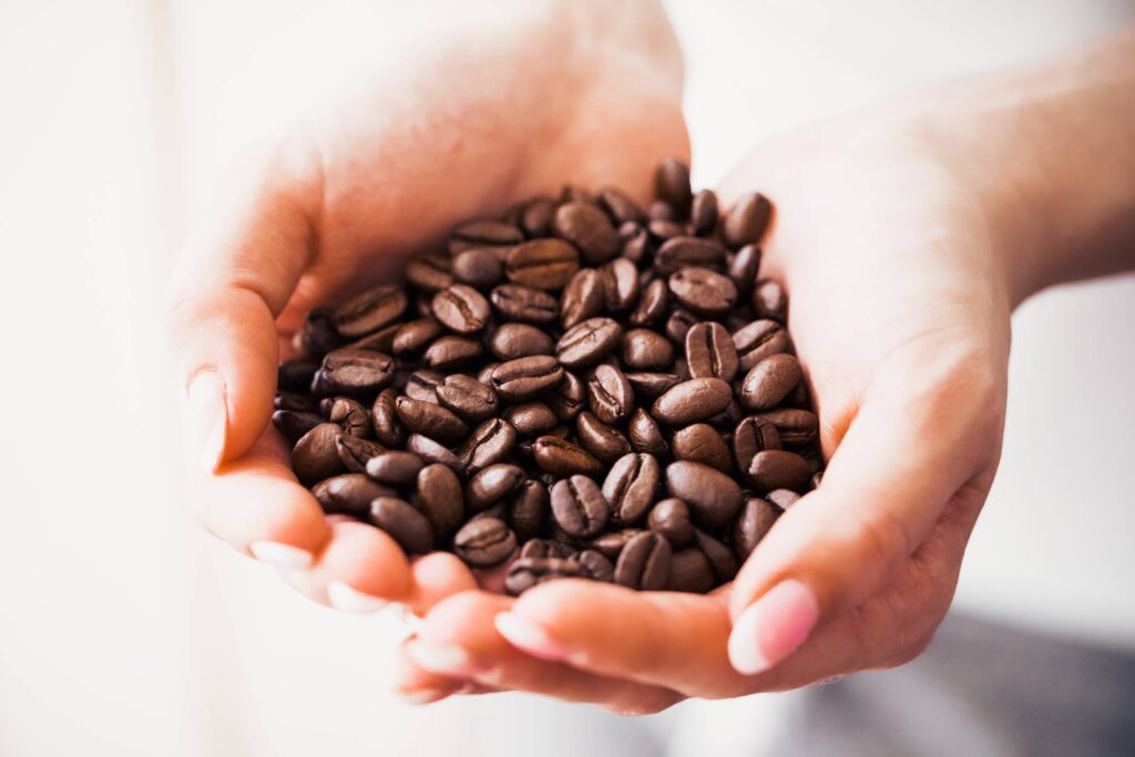 Woman Holding Handful of Roasted Coffee Beans Free Photo