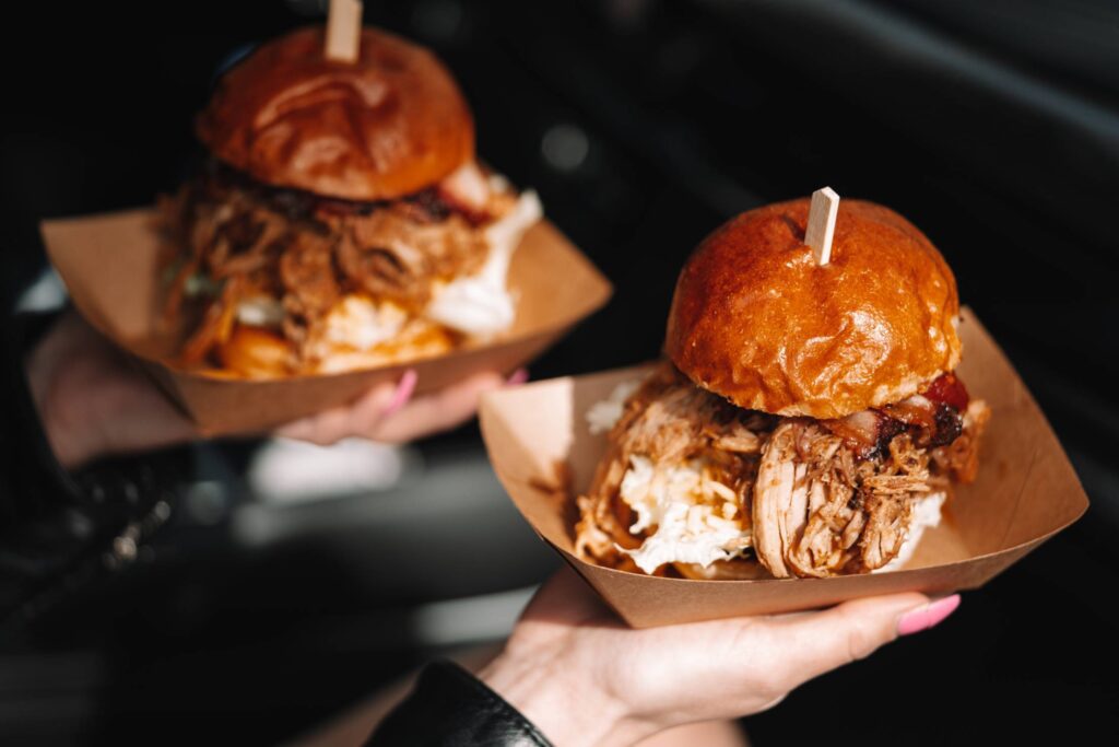 Woman Holding Two Burgers with Shredded Meat Free Photo