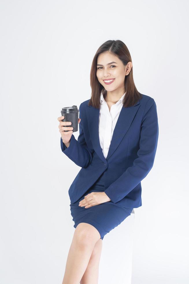 Woman in blue suit is drinking coffee on white background Stock Free