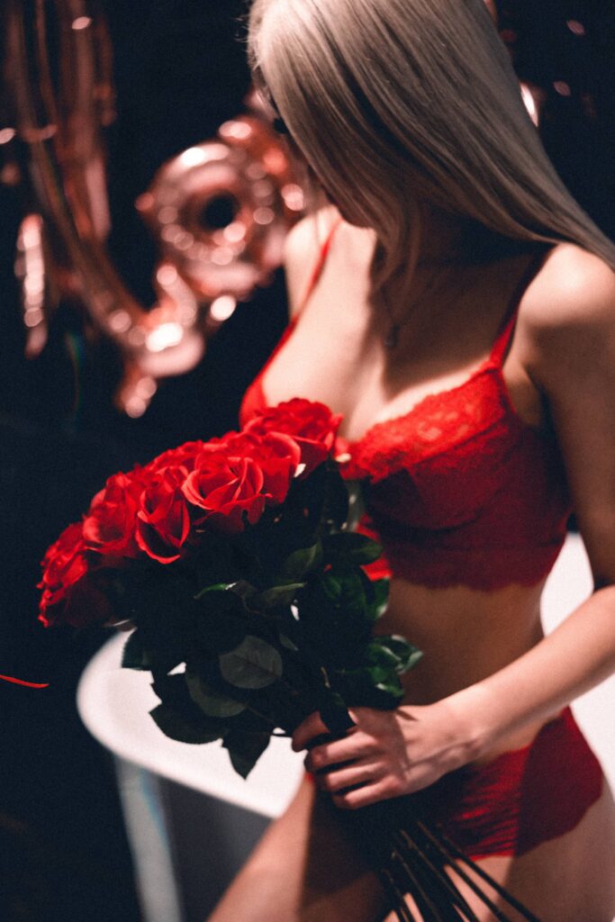 Woman in Red Lace Lingerie Holding a Bouquet of Roses Free Photo