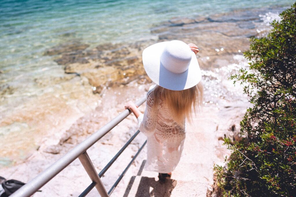 Woman in White Summer Hat Going for a Swim in the Sea Free Photo