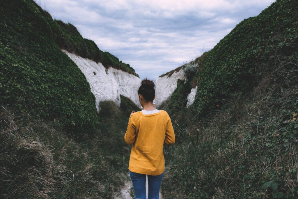 Woman in Yellow Mustard Sweater Between Hills Free Photo