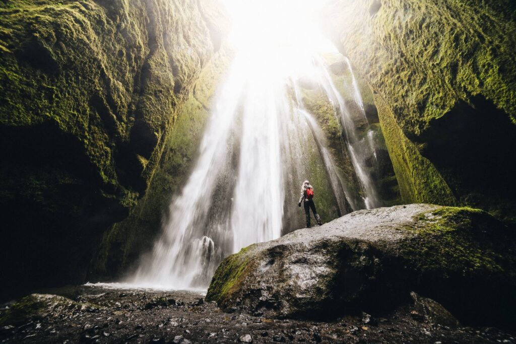 Woman Looking Up at Gljúfrabúi Waterfall Free Photo