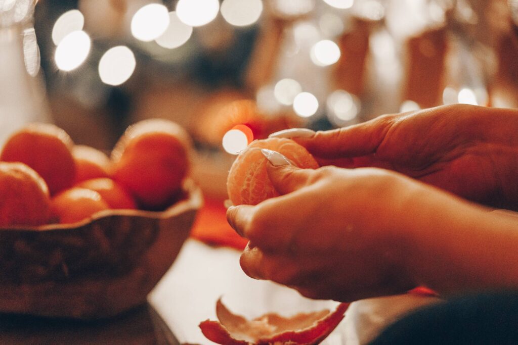 Woman Peeling a Tangerine During Christmas Holidays Free Photo