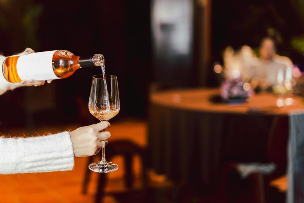 Woman pouring rose wine from bottle into glass lifestyle concept. Stock Free