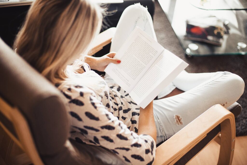 Woman Reading a Book in a Chair Free Photo