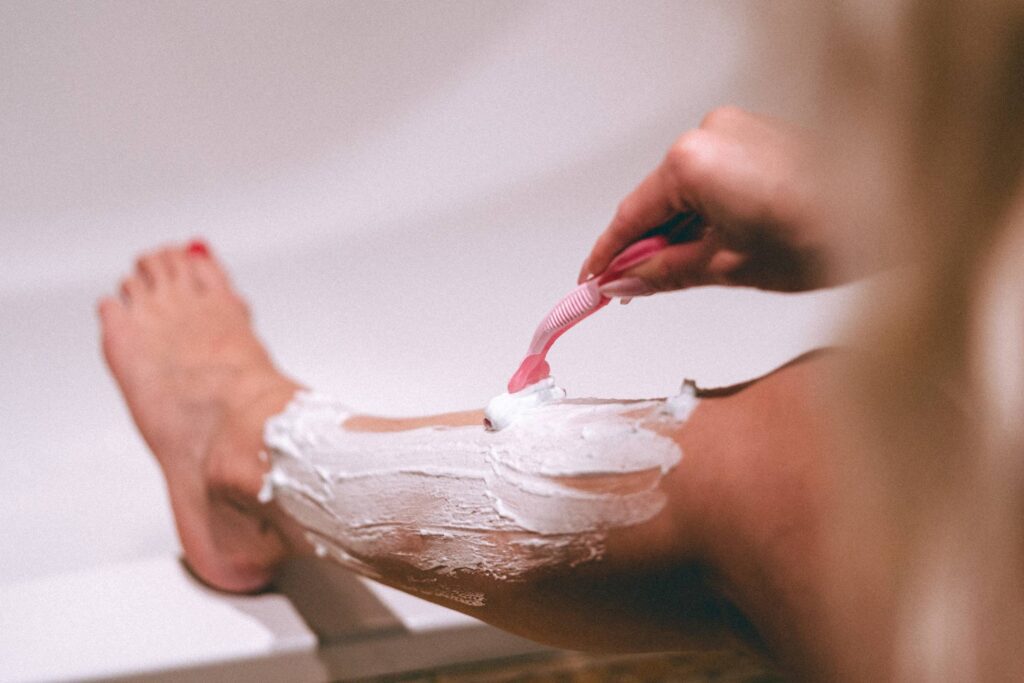 Woman Shaving Her Legs with a Pink Razor Free Photo