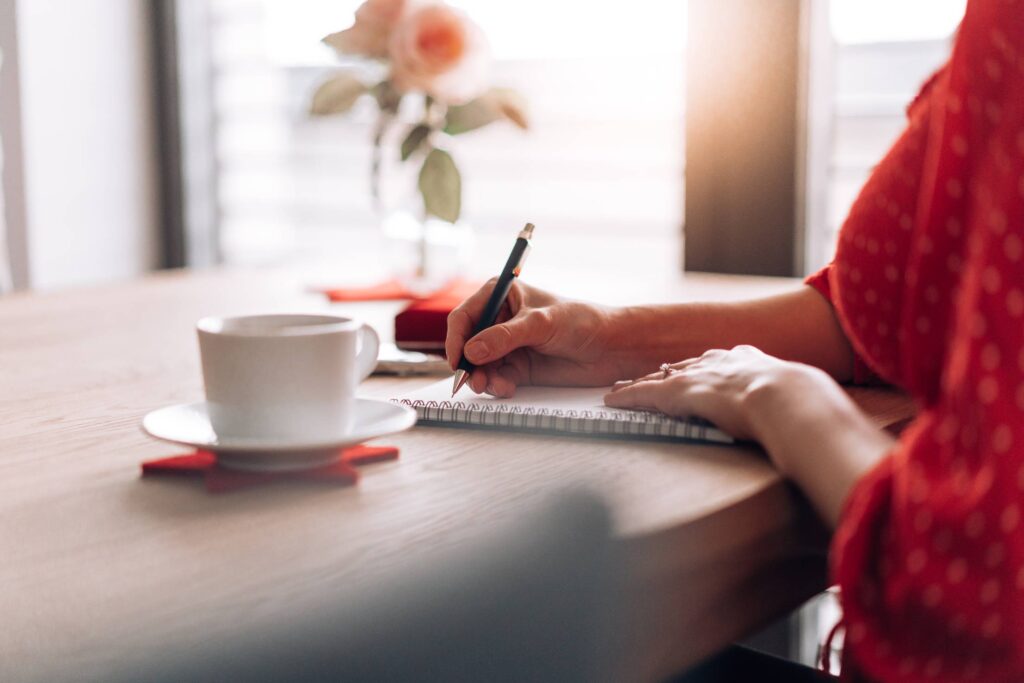 Woman Sitting at a Table and Writing in a Diary Free Photo