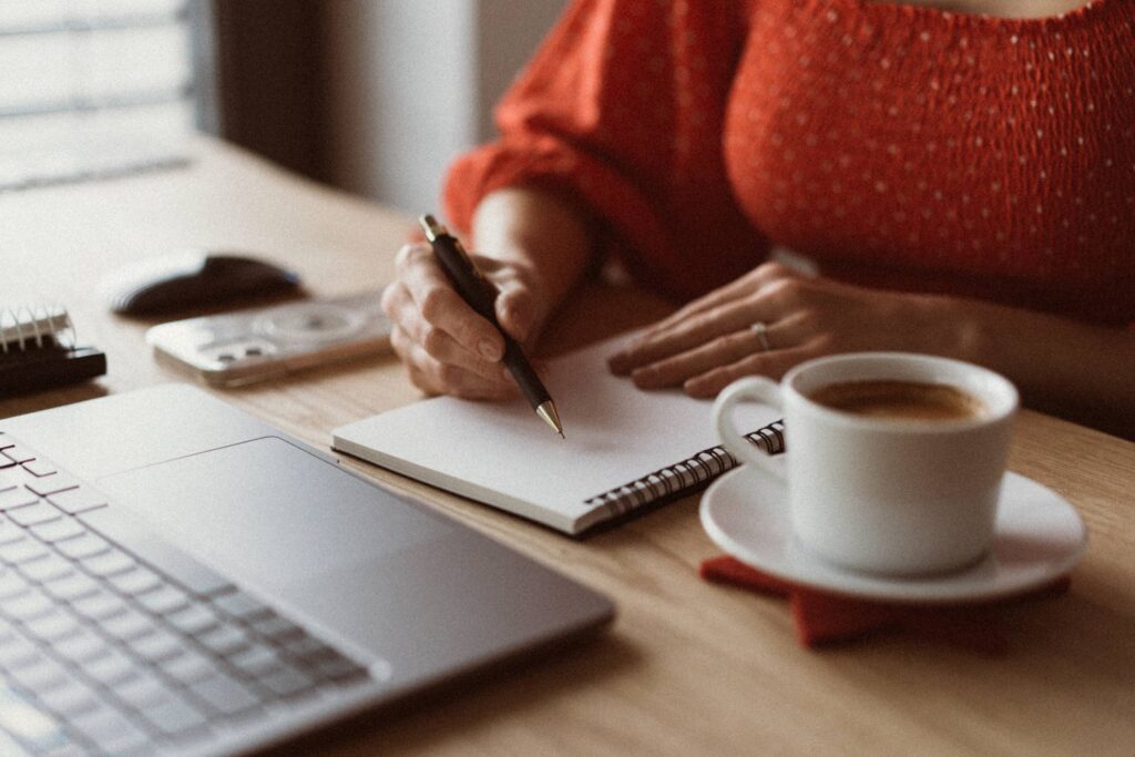 Woman Sitting at a Wooden Table and Writing in a Diary at Home Free Photo