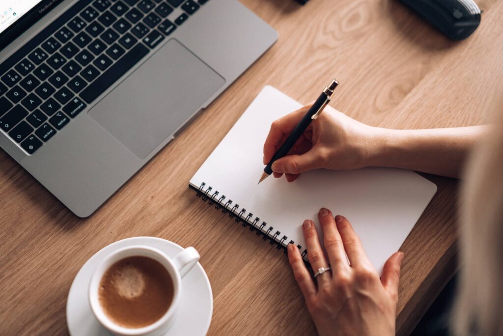 Woman Sitting at a Wooden Table and Writing in a Diary Free Photo