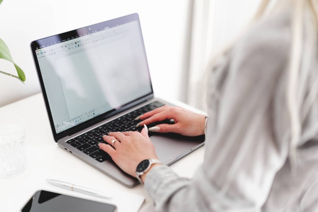 Woman Sitting at Desk and Typing on Laptop Free Photo