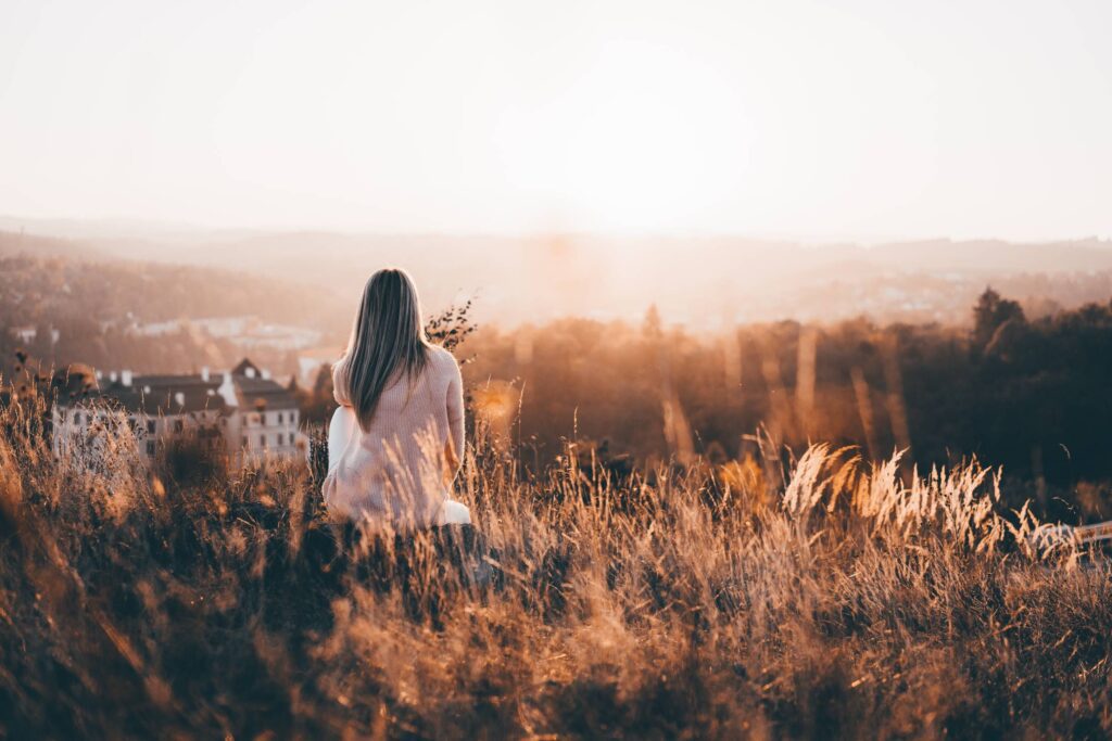 Woman Sitting on a Hill and Watching Nature Free Photo