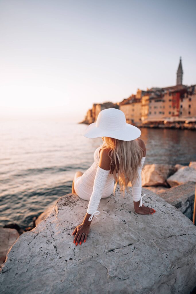 Woman Sitting on a Rock Shore Watching the Sunset in Rovinj Free Photo