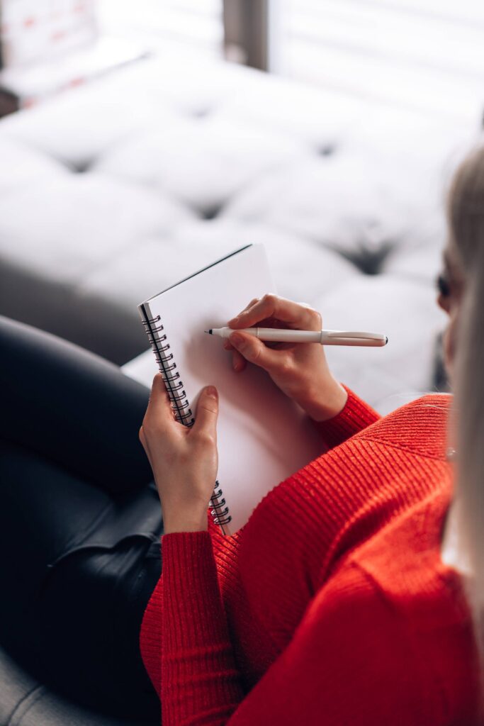 Woman Sitting on a Sofa and Writing in a Diary Free Photo