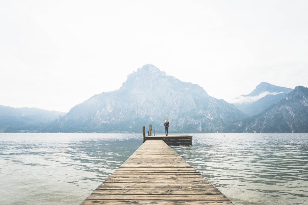 Woman Standing Alone on a Large Wooden Pier on a Lake Free Photo