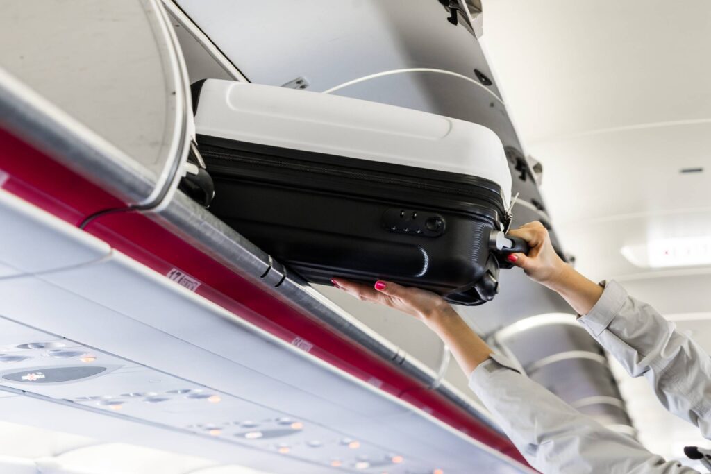 Woman Taking Her Hand Luggage in Airplane Free Photo