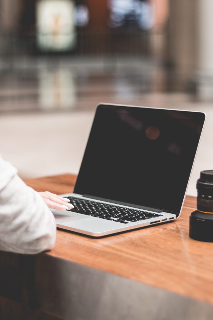 Woman Using a Laptop on a Wooden Table Free Photo