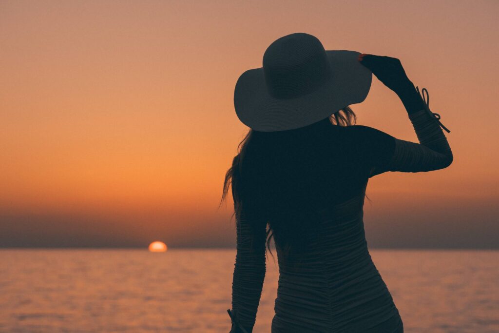 Woman with Summer Hat Looking at Dark Golden Sunset Free Photo